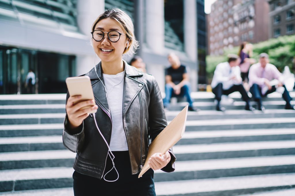 happy Chinese blogger with cellphone and notepad